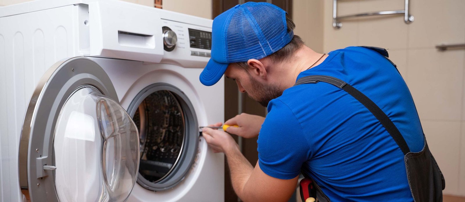 Working man plumber repairs a washing machine in home. Washing machine installation or repair. plumber connecting appliance.
